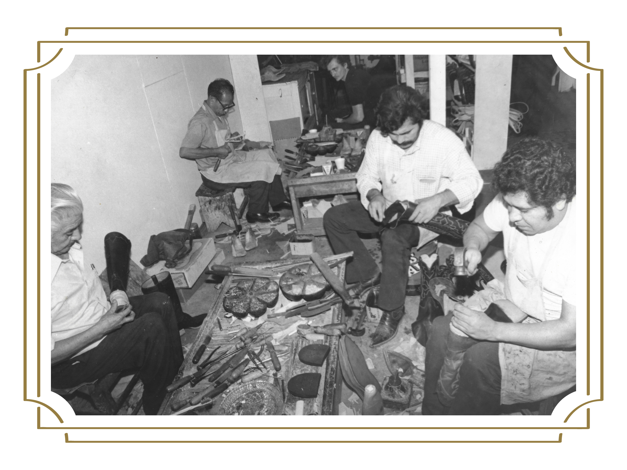 A black-and-white photo of four men seated in a workshop, crafting custom handmade cowboy boots using various tools and materials around them.