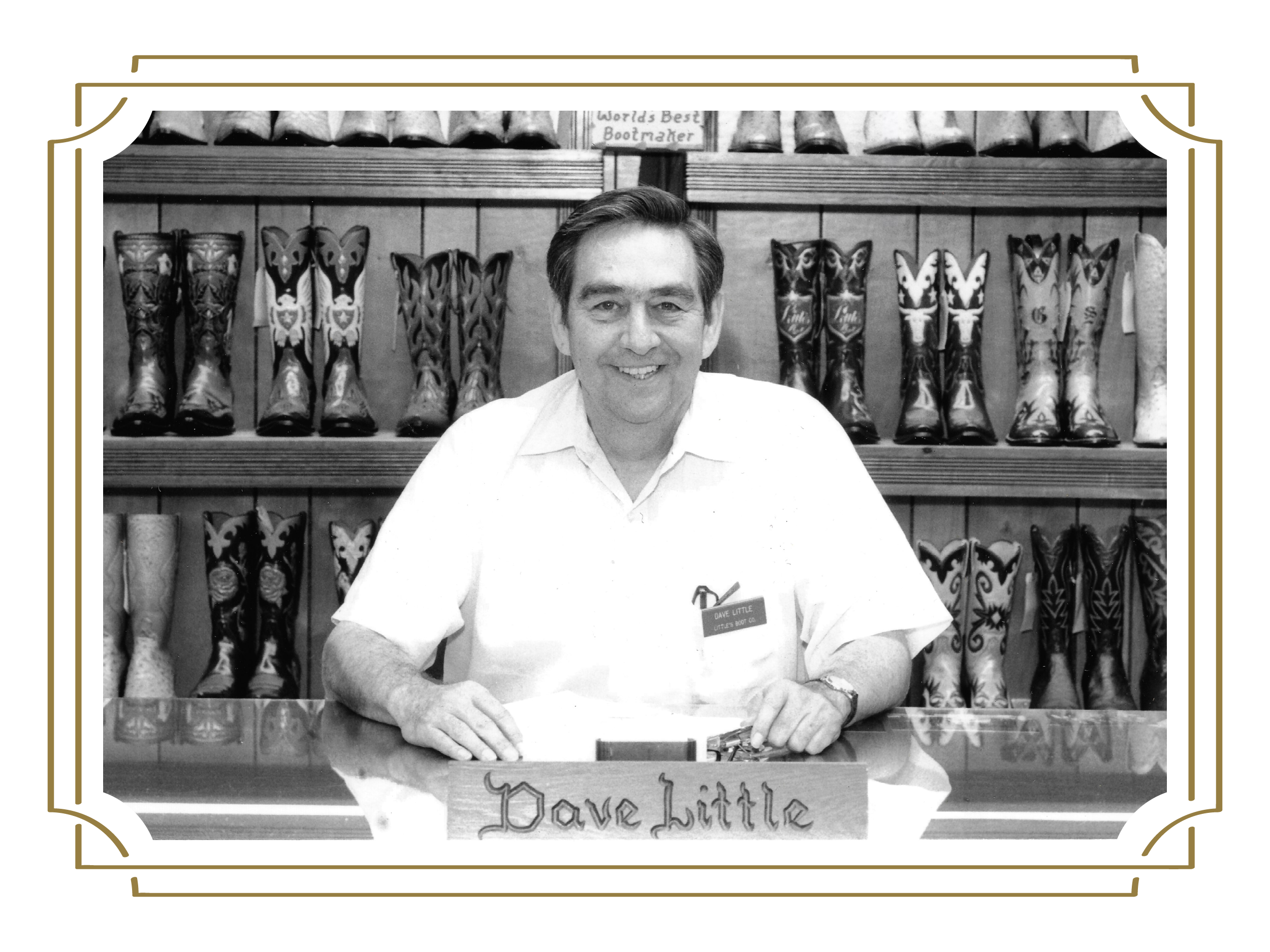A man in a white shirt stands behind a counter with a nametag "Dave Little" in front of a display of personalized luxury cowboy boots.