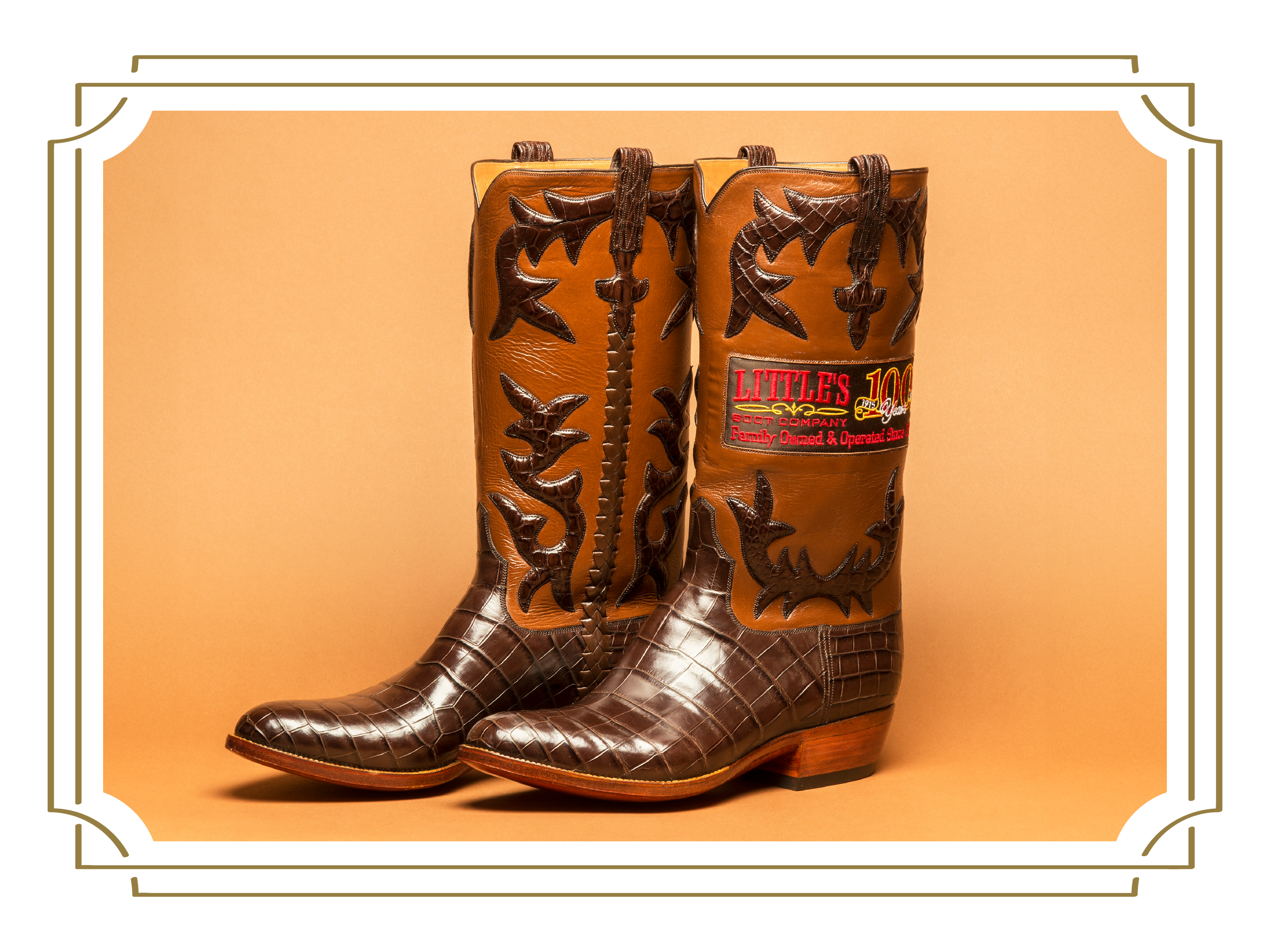 A pair of brown cowboy boots featuring decorative stitching, embossed patterns, and the Little's Boot Company logo on the side.
